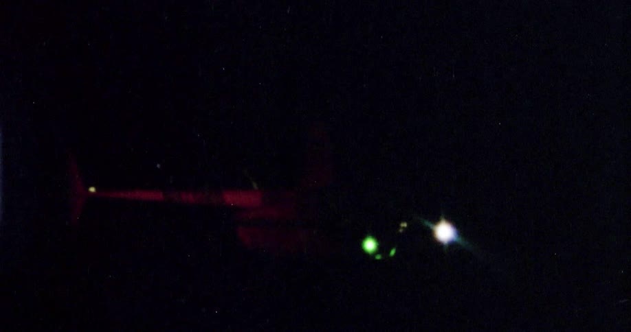 A red light on the tail of the helicopter flashes and glows as it flies at night