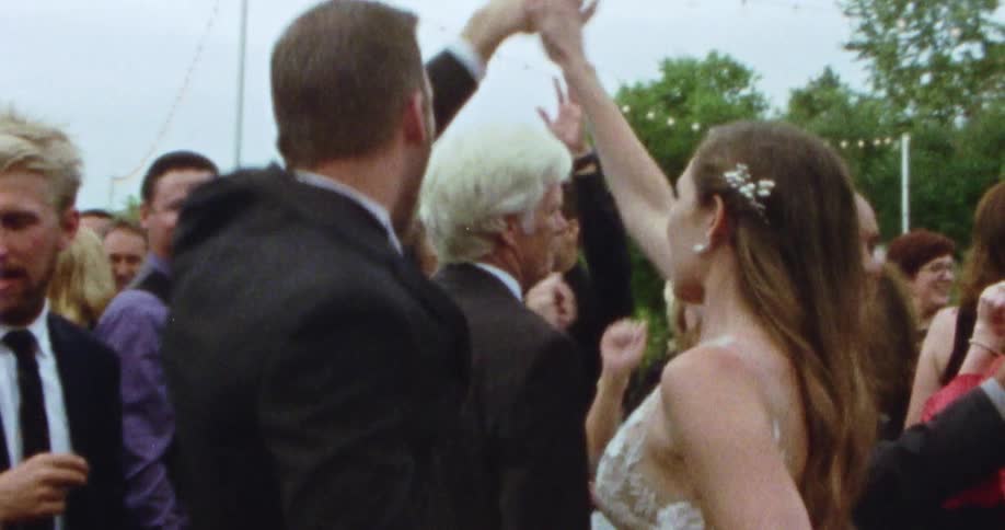 A man and a woman dance at a wedding party surrounded by guests