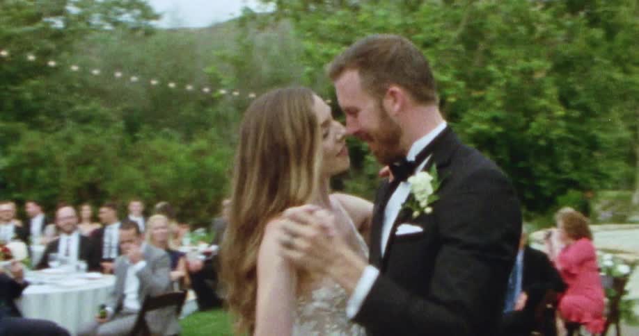A newly wedded couple dance at a wedding party held outdoors in a backyard