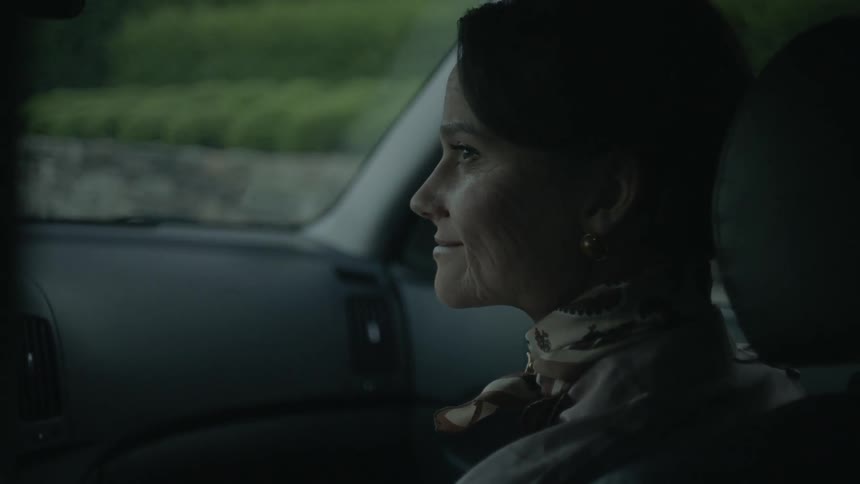 A woman sits in a passenger seat and smiles at the driver