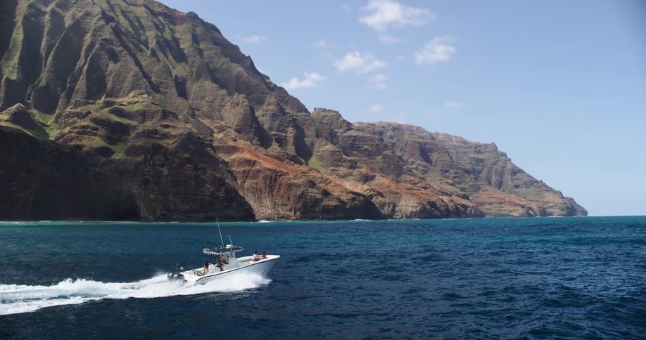 A boat moving in the ocean with a rocky coast and the sky in the background
