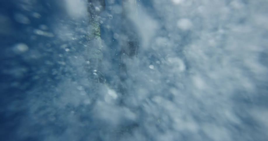 A person with flippers swimming underwater with bubbles