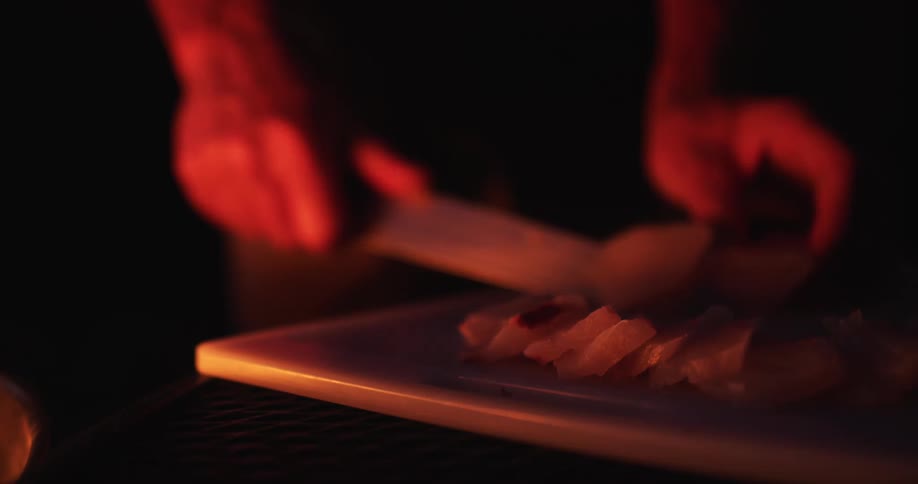 A person uses a knife to cut some fish