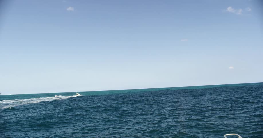 A private boat is headed away from a rocky coast on a beautiful day