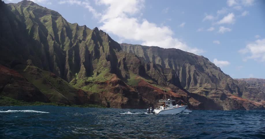 Boat sailing near the coast in front of a mountain range