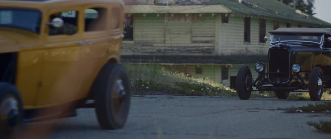 Three men drive classic cars through a run through neighborhood