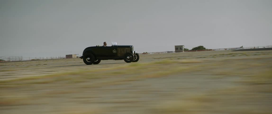 Vintage cars racing down a road