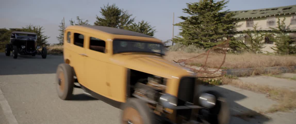 Vintage antique cars driving down a road