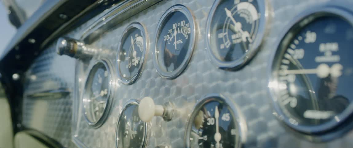 An elderly mans reflection on a dashboard as he drives a vintage car