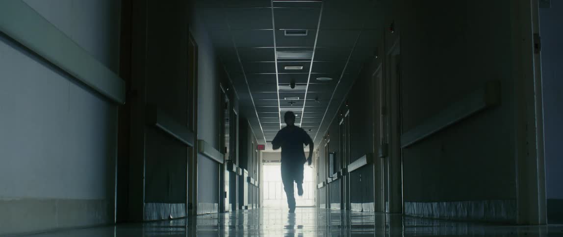 A doctor runs down a corridor in a hospital