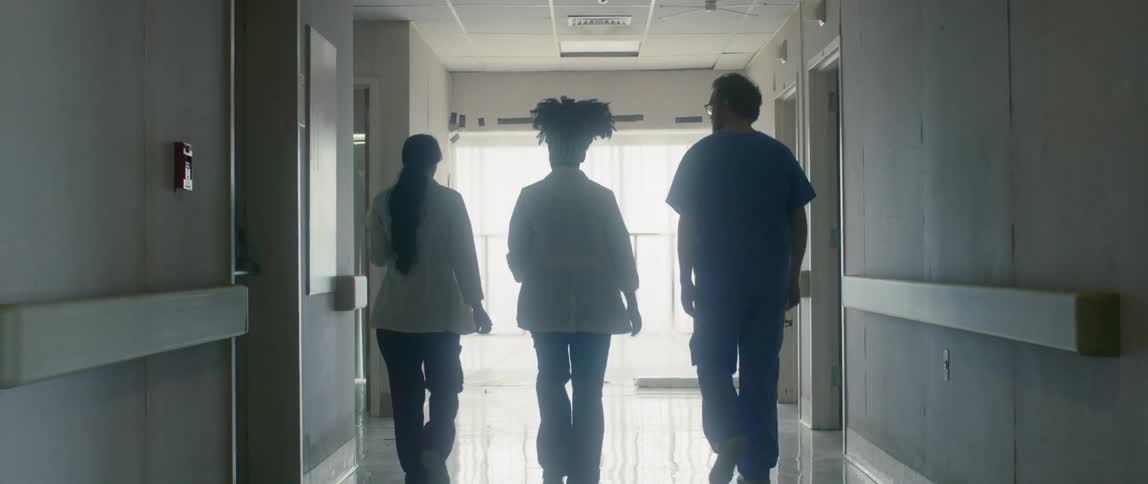 Three doctors walk down the hallway of a hospital together and turn a corner