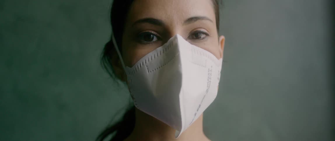 Female nurse wearing face mask looks at the camera