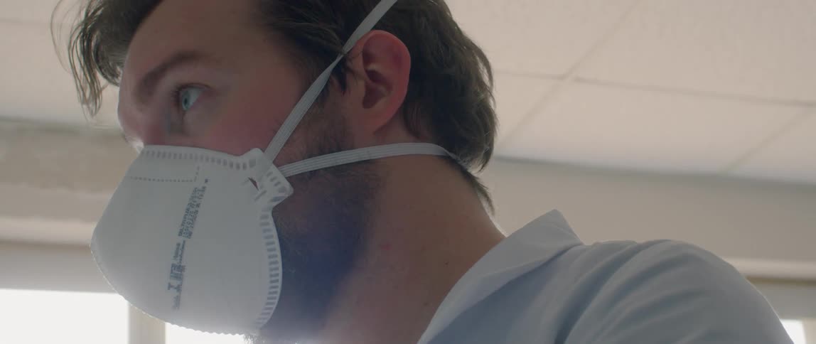 A man puts glasses on and tightens his face mask to fit around his nose