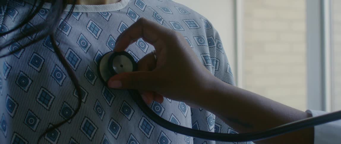 Medical professional listens to a womans heart with a stethoscope