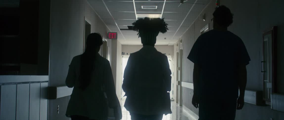 Three people walk down the hospital hallway