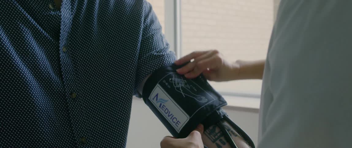 A female doctor wrapping a blood pressure meter around the arm of a male patient