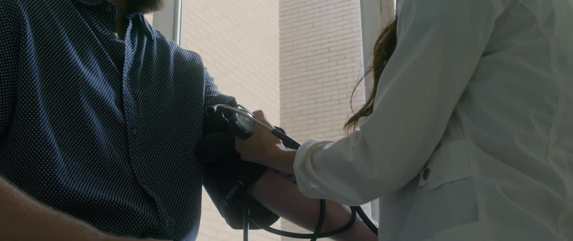 A doctor takes a blood pressure cuff off a patient