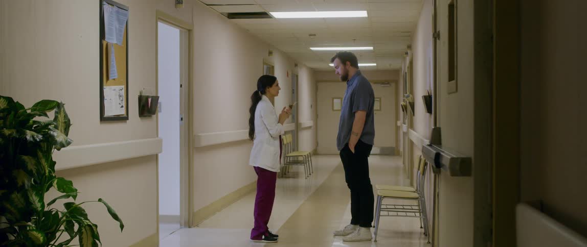 A doctor comforts a man in a hallway at a hospital