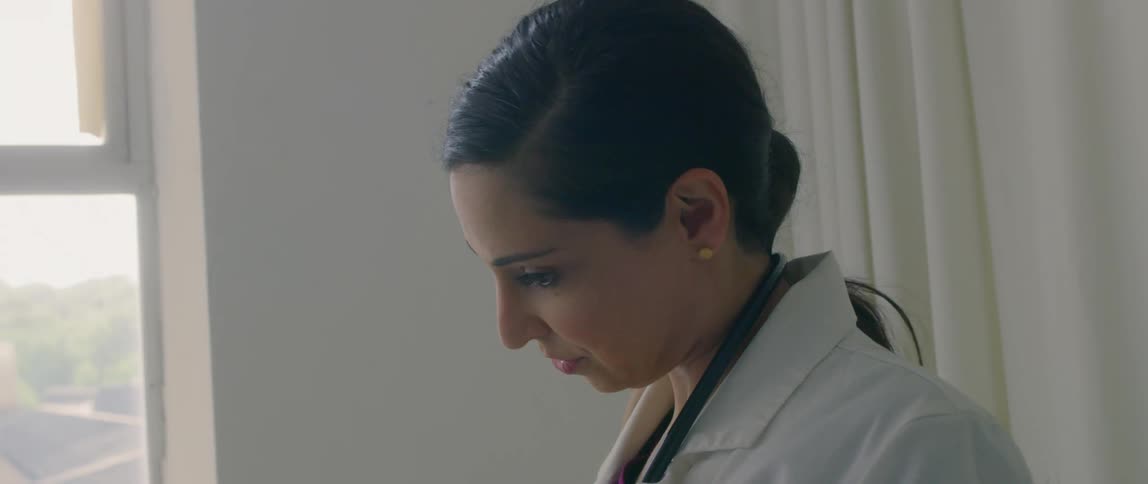 A doctor smiles as she puts on her stethoscope around her neck