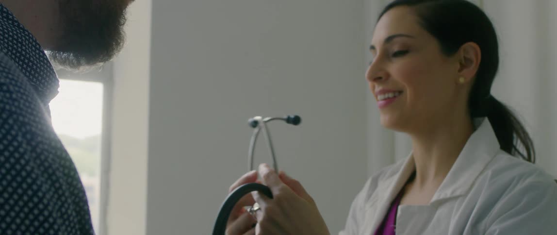 A doctor pulls her stethoscope from around her neck to check a patient