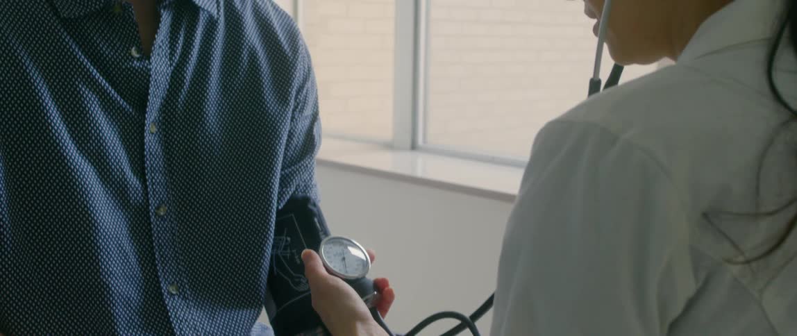 A female doctor measuring the blood pressure of a man in glasses