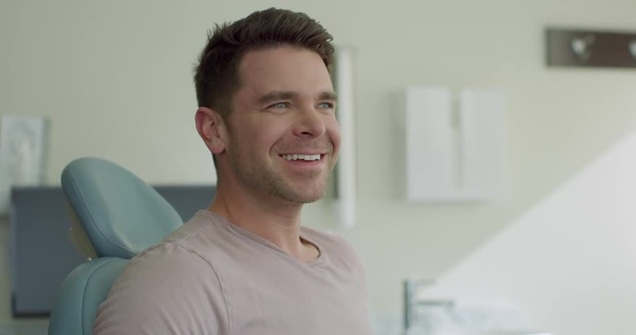 Man smiles and talks as he sits in a dentists chair