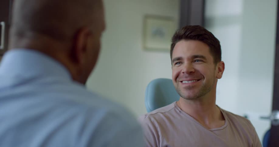 Patient sitting in dentist chair greets dentist and starts talking