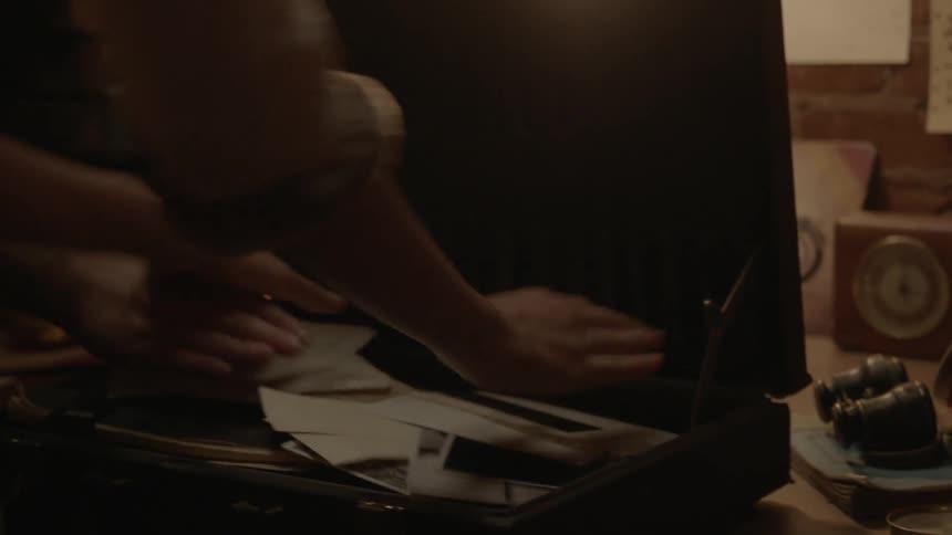 A person quickly grabs a bunch of items and puts them in a briefcase