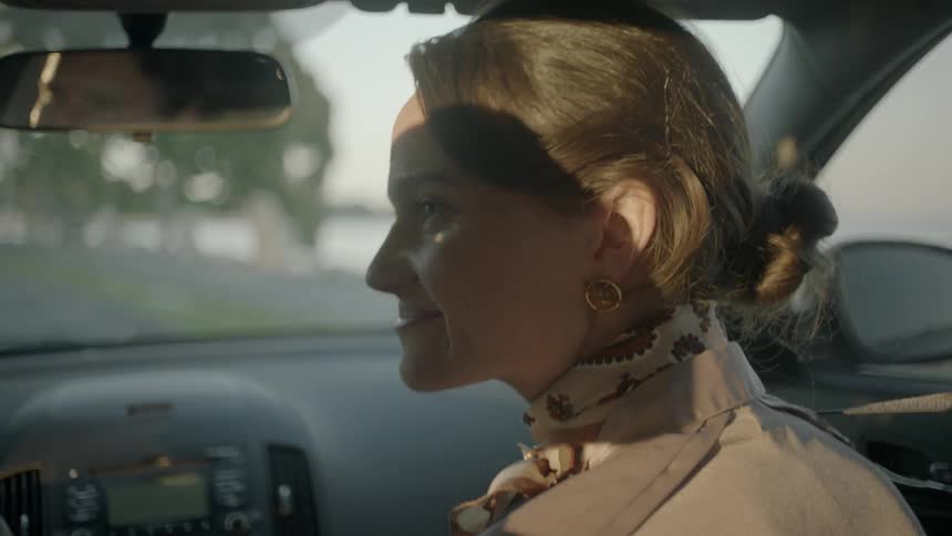 A woman sitting in the passenger seat of a moving car turns and talks