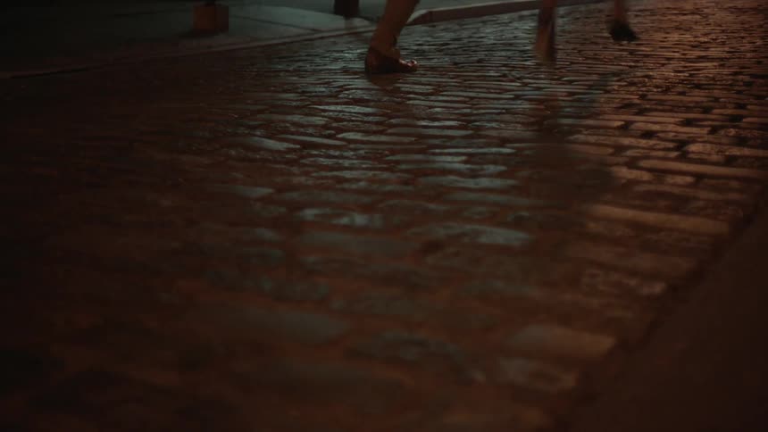 Two people can be seen running down a cobblestone sidewalk