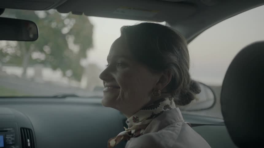 A woman sitting in the passenger seat is looking over and smiling