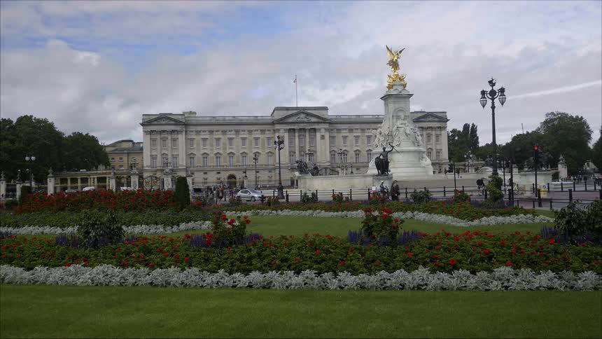 People and cars pass in front of Buckingham Palace