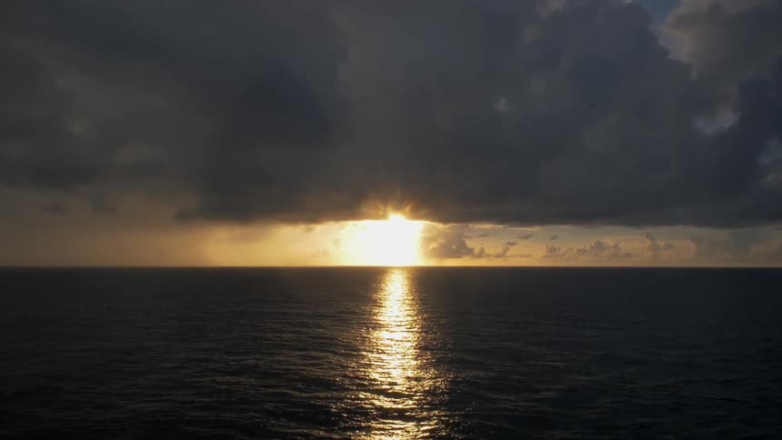 The sun is setting in the distance beyond a huge body of water