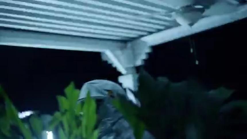 A person takes cover on a porch during a storm