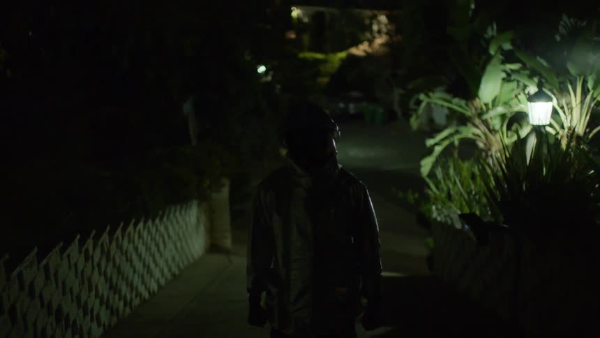 A man stands outside in protective gear as lights flash