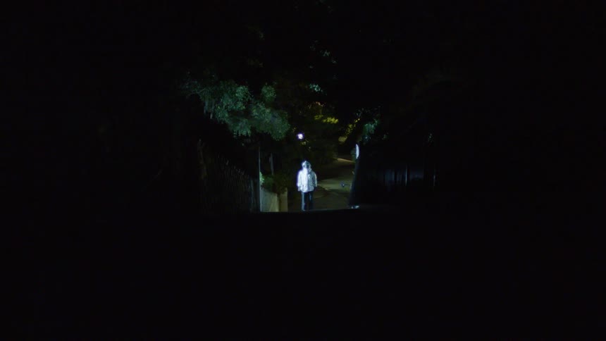 A person stands outside as lightning flashes and a helicopter flies overhead