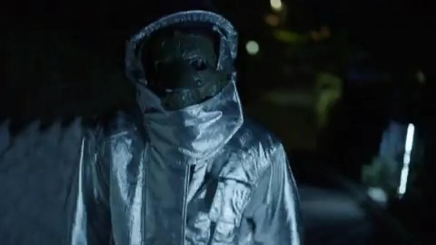 A person in a hazmat suit walks down the dark street