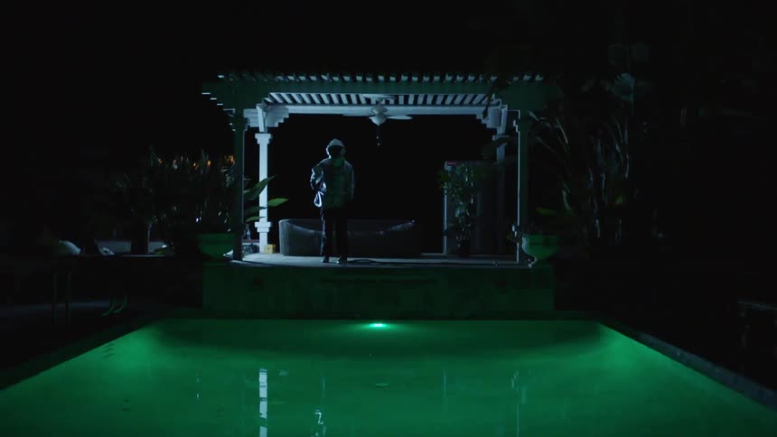 A man stands under a gazebo as lightning flashes around him