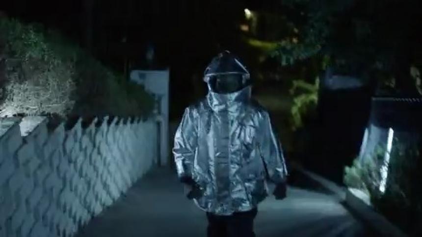 A person in a hazmat suit walks on the sidewalk