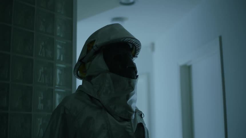 The lights in the hall are flashing on the person in the hazmat suit