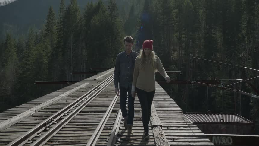 A man and woman are walking along a bridge on a cloudy day