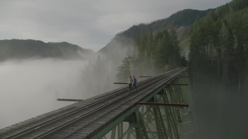 People are walking along a bridge on a foggy day