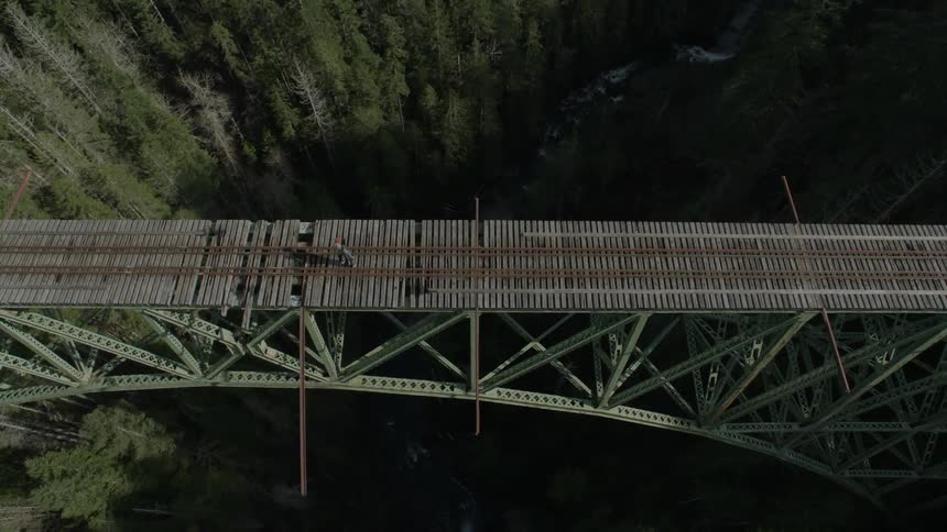 A person is looking down from the tracks on a bridge