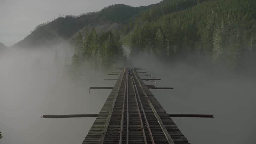 Heavy fog is directly under a bridge with train tracks