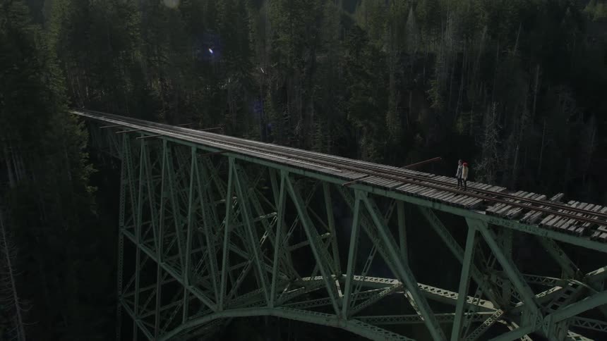 People are standing on a bridge with a train track
