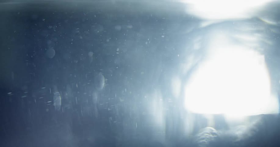 Water splashes on a window as a light passes by