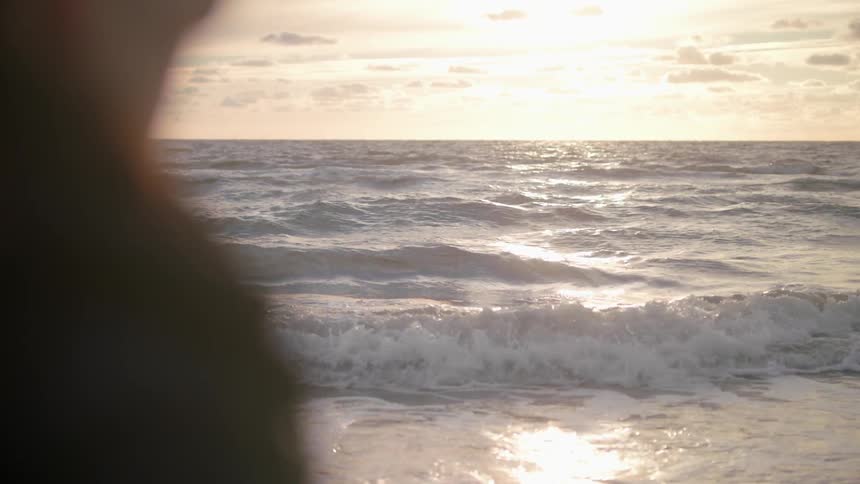A person is watching heavy waves as the sun rises