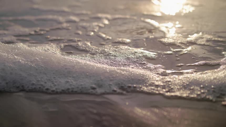 Foamy ocean waves slowly washing over the beach