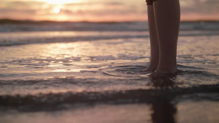 Person standing ankle deep in gentle ocean waves