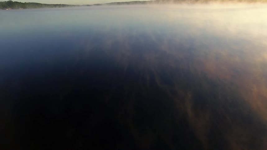 Fog covers a large lake on a cloudy day